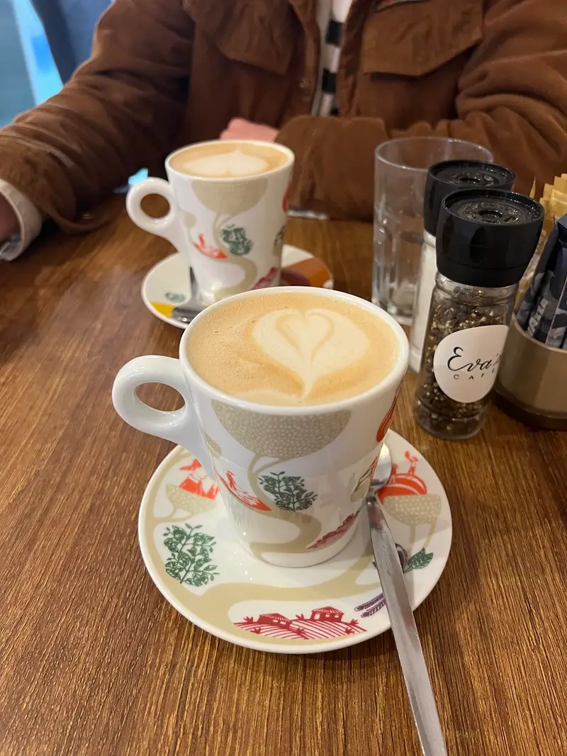 Two Lavazza lattes with heart art in decorative cups at Eva's Cafe