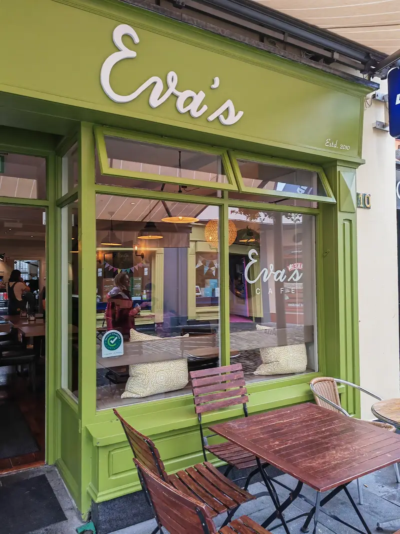 Close-up of Eva's Cafe storefront with Estd. 2010 signage and green paint scheme