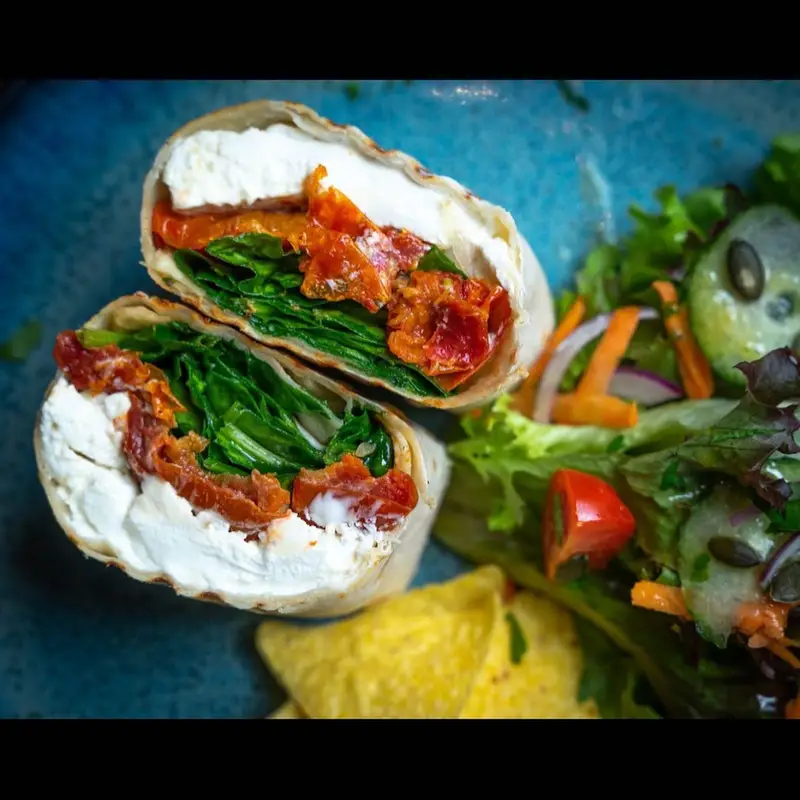 Fresh wrap with spinach, roasted peppers, cream cheese, side salad and tortilla chips